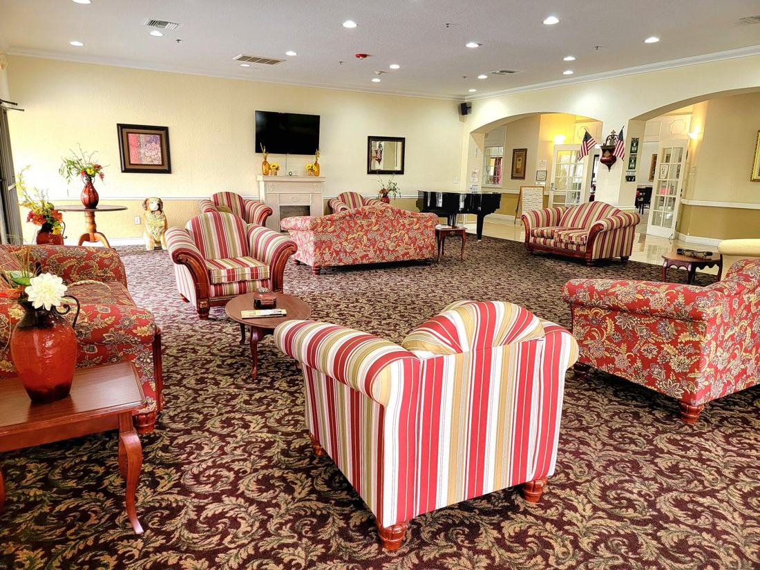 Shared living room with striped sofas and chairs on patterned carpet at Sunny Hills in Homestead